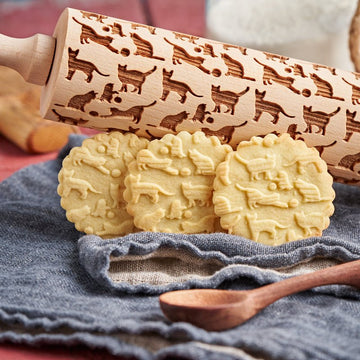 Cats pattern engraved on a wooden embossed rolling pin, beside the shortbread cookies it prints