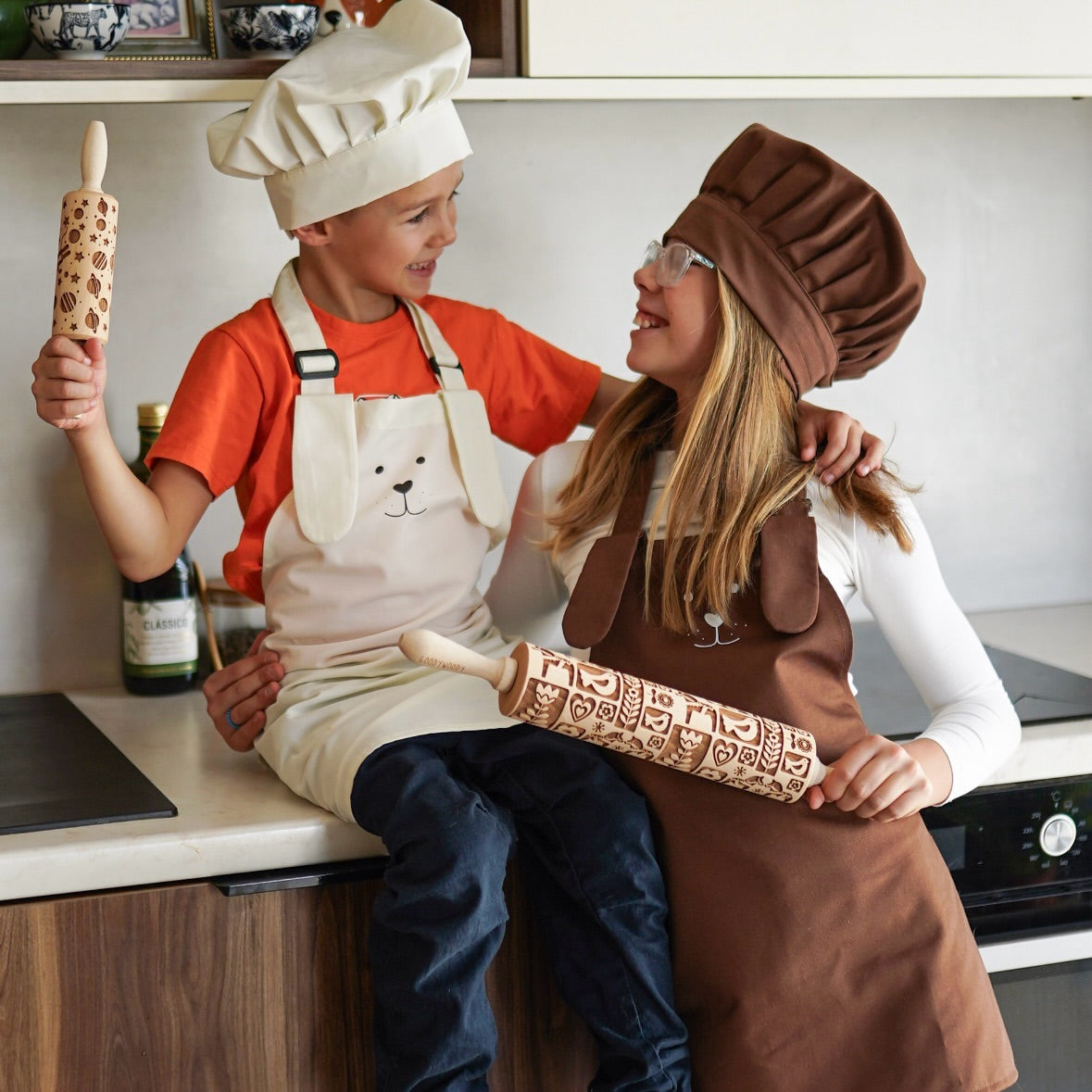 Two children in aprons and chef hats holding Pastrymade embossed rolling pins
